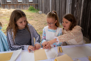 young girls rolling beeswax candles at Fort Ross