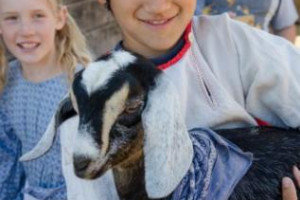 Happy children in traditional Russian attire holding a goat